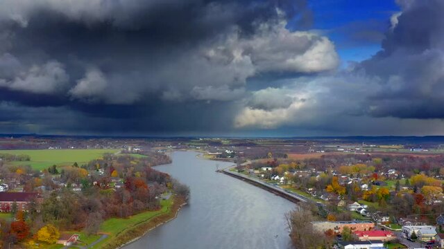 Dark storm clouds hang heavy over bridge across Autumn river
