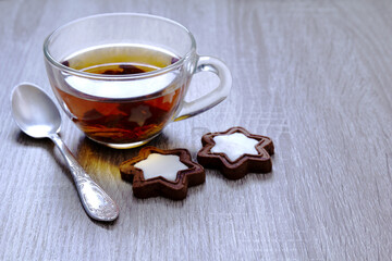 A cup of black tea made from a large leaf stands on the table. There are biscuits and teaspoon...