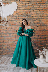 A beautiful girl in a green dress smile shows a brick wall dress