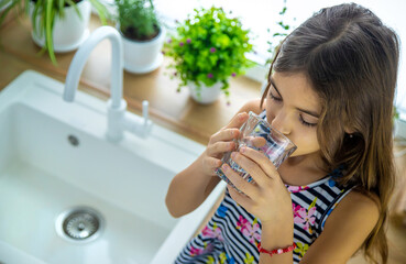 Children drink tap water at home. Selective focus.