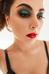 Glamorous colorful portrait of a beautiful young woman with makeup, red lips and green eyeshadows on a white background in the studio