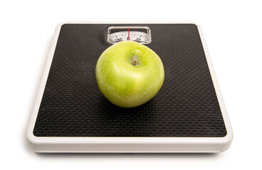 Green apple on a bathroom scale on a white background