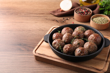 Tasty cooked meatballs served on wooden table. Space for text