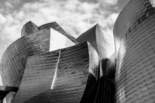 Bilbao, Spain - April 22, 2021: Guggenheim Museum titanium shapes facade in Bilbao city. Modern building architecture designed by Frank Gehry. Black and white photography