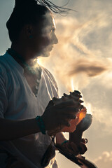 Hombre de perfil a contraluz en una ceremonia maya con un caracol en la mano