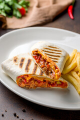 Mexican chicken burrito on white plate on dark brown concrete table