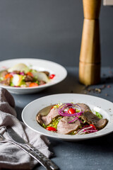Salad with roast beef and vegetables on grey table , vertical, selective focus