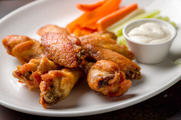Buffalo chicken wings with blue cheese sauce on dark brown concrete table close up