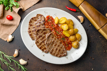 beef chops with fried potatoes top view on dark brown table