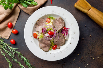 Salad with roast beef on dark brown concrete table top view