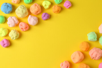 Fototapeta premium Different color play dough on yellow background, flat lay. Space for text