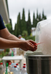 Preparation of cotton candy in nature. Men's hands wind cotton candy on a stick.