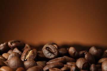 Heap of aromatic roasted coffee beans on brown background, closeup