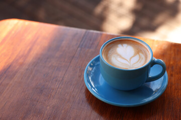Ceramic cup of aromatic coffee with foam on wooden table in outdoor cafe. Space for text