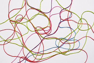 Red, green, pink, blue threads are scattered on a gray background. Yarn for creativity.