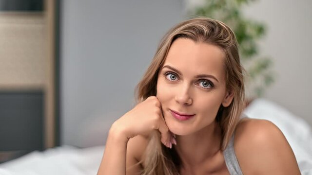 Closeup portrait blonde woman relaxing posing lying on bed enjoying laziness morning at home