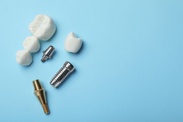 Parts of dental implant and bridge on light blue background, flat lay. Space for text