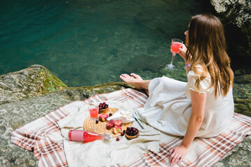 Cozy summer picnic near the lake with wine, cherry, peaches, brie cheese, camamber. Romantic picnic...