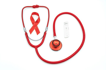 Top view photo of red stethoscope with red silk ribbon symbol of aids awareness and Test kit for...