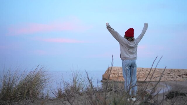 Carefree happy young woman enjoying beautiful sunset on the beach. Concept of detachment and mental balance.