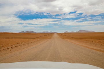 Fototapeta na wymiar Endless and lonely road through the desert going into the mountains of Namibia