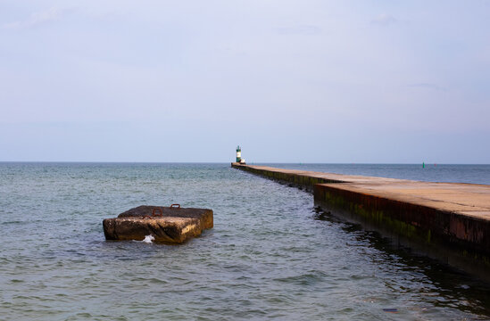 Old green and white light house in the end of the pier. No people on the photo, calm relaxing atmosphere, free copy space for text