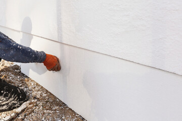 Construction Worker Installing Styrofoam Insulation Sheets on House Facade Wall for Thermal Protection.