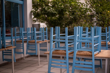 Fototapeta na wymiar Blue chairs and tables stacked outside closed cafe-restaurant during the Coronavirus lockdown.
