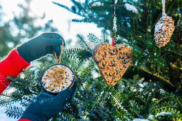 Feeding birds in winter. Woman with bird food.