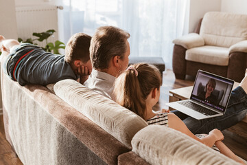Video conference. Social media. Dad and the children are sitting in the living room and calling mom via video link. Communication, meetings online