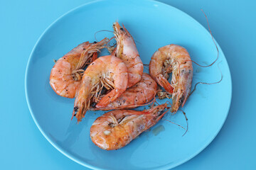 Boiled shrimps on blue plate. Healthy sea food.