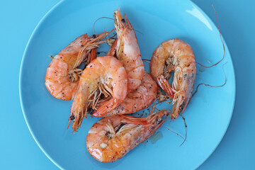Boiled shrimps on blue plate. Healthy sea food.