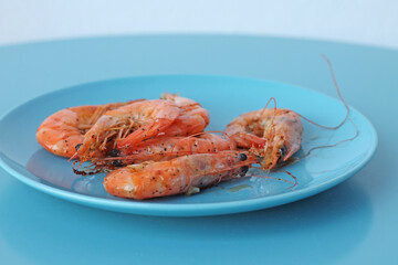 Boiled shrimps on blue plate. Healthy sea food.