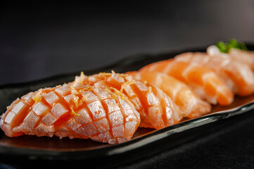 Truffle salmon onigiri, salmon on black plate.
