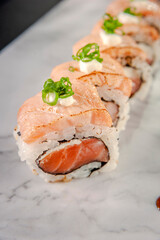 Uramaki blowtorcherd salmon in marble plate.