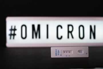 a positive Covid antigen rapid test lies next to a light panel with the inscription #Omikron.