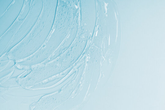 Abstract cosmetic background from thick transparent gel or antiseptic, hyaluron on blue background