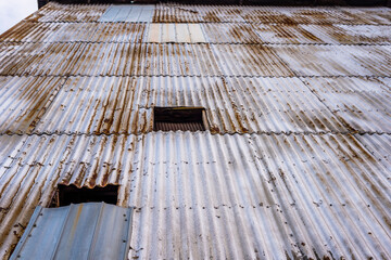 Looking up the exterior of a building clad in rusty corrugated metal.