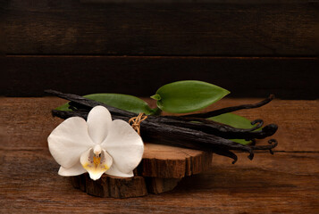 Vanilla green leaves ,dried pods on an old wood background.