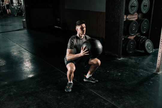 A strong man doing functional exercises with medicine ball at the gym.