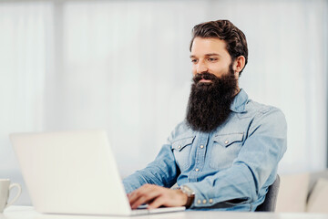 A young freelancer sitting at home and working on the laptop.