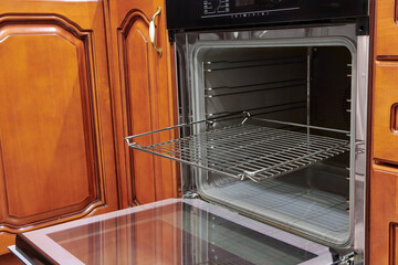 Opened door of the electric oven. Modern black kitchen oven. Build-in kitchen appliance. Equipment for cooking.
