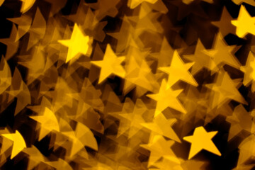 Golden stars lights bokeh on dark background. Concept of Christmas and Happy New Year. Abstract...