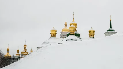 Foto op Canvas Golden domes of Kiev Pechersk Lavra or Kyiv Monastery of Caves behind a snowy slope on cold winter day. Cupolas of famous orthodox church on Dnipro river bank, Ukraine © Julia Lavrinenko