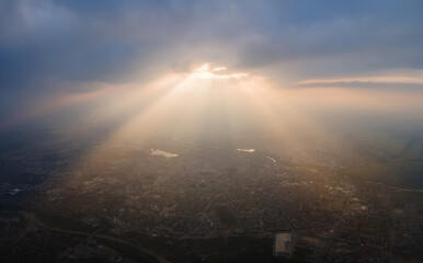 Aerial view from high altitude of distant city covered with puffy cumulus clouds forming before...
