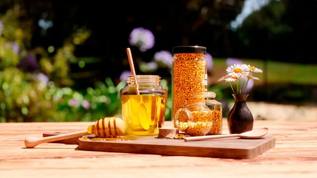 A jar of honey, dipper, wooden scoop and glass pots full of bee pollen granules