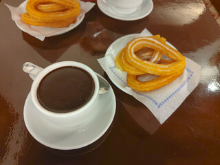 Traditional, typical spanish churros with hot chocolate sauce on a rustic wooden table
