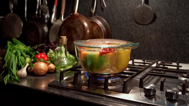 Cooking stuffed peppers, in boiling water, on the stove in a transparent saucepan, dolly shot