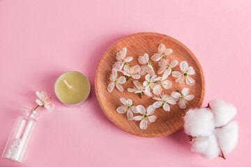 Relaxation spa and aromatherapy concept. Candles, essential oil and flowers. Natural organic cosmetics on a pink background.