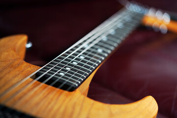 Fototapeta premium Guitar wallpaper. Musical instrument. Performance. Art. Strings. Electric guitar closeup detail. Music. Play. Wooden vintage guitar. Ukulele 